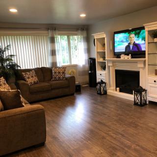 A cozy living room with a sofa, television, and fireplace on hardwood floors.