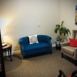 A cozy living room with a blue sofa, beige armchair, and warm lighting.