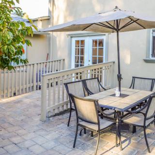 A cozy outdoor patio with a dining set and umbrella, perfect for enjoying sunny weather.