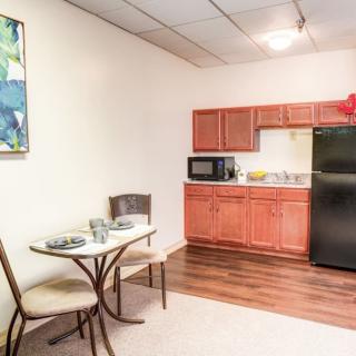 A compact kitchen and dining area with a table, chairs, microwave, refrigerator, and cabinets.