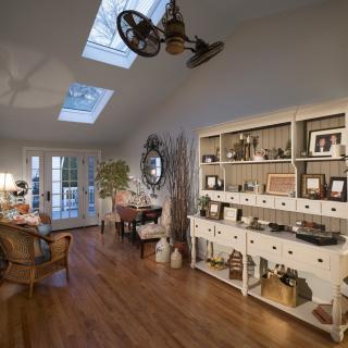 A cozy vintage-style living room with wooden floors, skylights, and a decorative bookshelf.