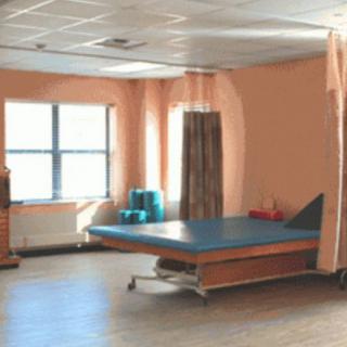 A spacious physical therapy room equipped with a treatment table and gym equipment.