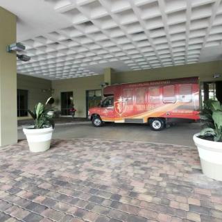 A delivery truck parked under a covered area with decorative plants.