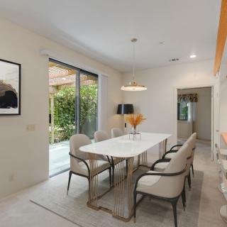 A modern dining room with a sleek table and comfortable chairs, featuring stylish decor and a large window offering natural light.