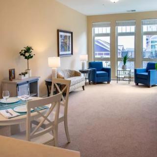 A modern living room with cozy seating and a small dining area.