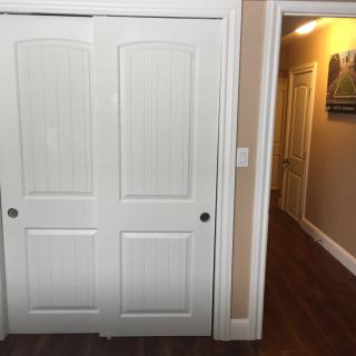 A hallway with a white sliding closet door and wooden flooring.