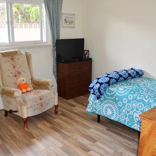 A cozy bedroom with a single bed, armchair, and television.