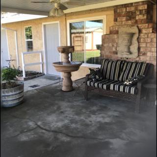 A cozy patio with a bench and stone fountain against a brick wall.