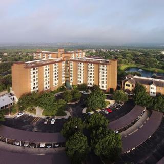 Aerial view of a modern hotel surrounded by green landscape.