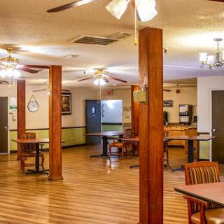 A spacious dining area featuring wooden tables, ceiling fans, and warm lighting.