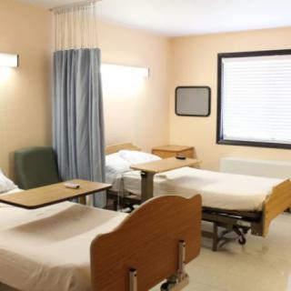 A hospital room with two beds and a dividing curtain.