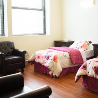 A cozy bedroom with twin beds, floral bedding, and an armchair by the window.