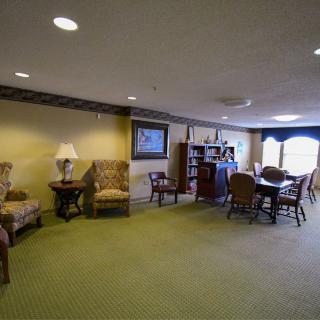 A cozy living room with seating area, bookshelf, and a dining table.