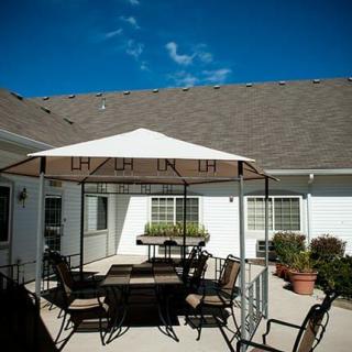 A sunny patio with a gazebo, outdoor furniture, and potted plants.