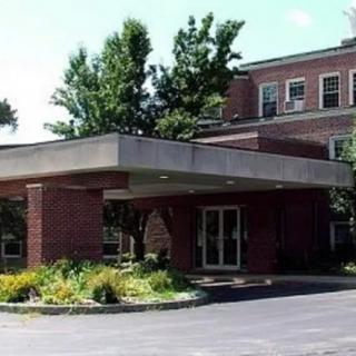 A brick hospital entrance with landscaping and a covered driveway.