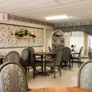 A cozy dining area with multiple tables and chairs, adorned with decorative wall art and curtains.
