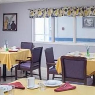 A neatly arranged dining area with tables set for a meal, featuring yellow tablecloths and red napkins.