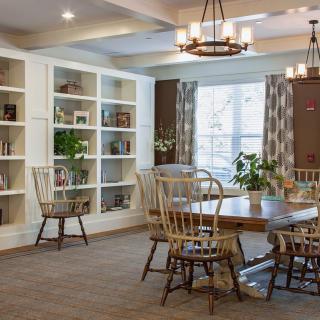 A cozy reading room with a large bookshelf, table, and chairs.