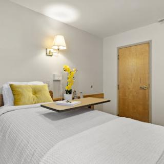 A cozy and modern bedroom featuring a comfortable bed with yellow accents and a bedside table.
