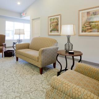 A cozy living room with beige sofas, a patterned carpet, and modern lamps.