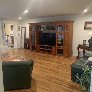 A cozy living room with a wooden entertainment center, television, and comfortable seating.