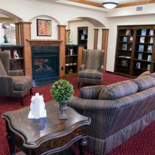 A cozy living room with a fireplace, sofas, armchairs, and bookshelves.