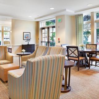 A bright and inviting seating area with comfortable chairs and tables, accented by large windows and light-colored decor.