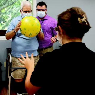 A physical therapy session where a patient is engaging in an exercise with the assistance of healthcare professionals.