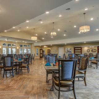 A spacious and elegantly designed dining area with well-arranged tables, chairs, and ambient lighting.