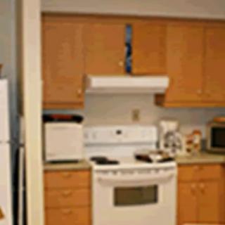 A kitchen with wooden cabinets, a stove, and various appliances on the countertop.