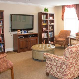 A cozy living room with a television, bookshelves, and comfortable seating.