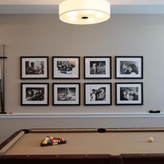 A stylish game room featuring a pool table and framed photographs on the wall.