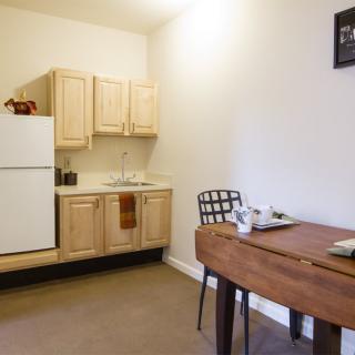 A cozy kitchen and dining area featuring wooden cabinets and a simple table with chairs.