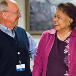 Two people are smiling and having a conversation indoors.