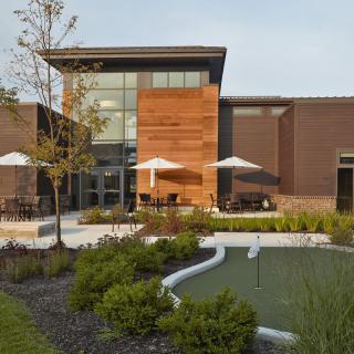 A modern building with outdoor seating and a landscaped garden featuring a small pond.