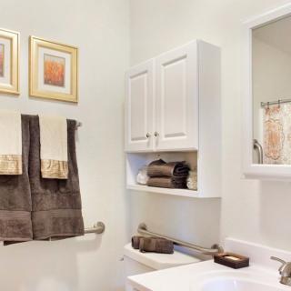A neatly organized bathroom with wall-mounted cabinets, towels, and decorative elements.