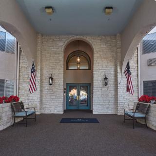 A building entrance featuring stone walls, an arched doorway, and American flags on either side.