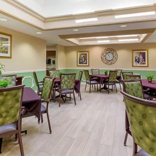 A well-lit dining area with multiple tables and chairs, decorated with artwork on the walls.