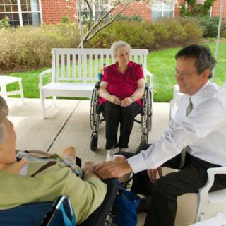 A warm moment of connection among elderly individuals and a caregiver outdoors.