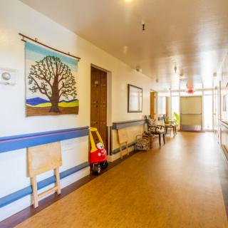 A brightly lit hallway with artwork on the wall and children's furniture.