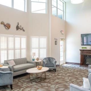 A bright and inviting living room featuring comfortable seating, a fireplace, and large windows.