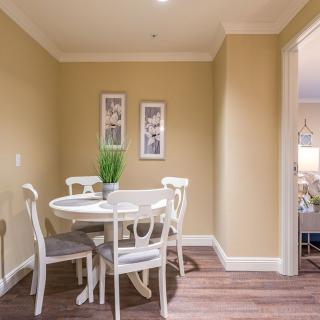 A cozy dining area featuring a round table with chairs, complemented by an indoor plant and wall art.