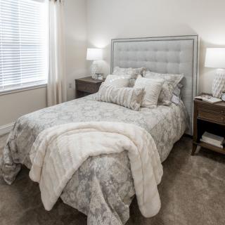 A cozy bedroom with a neatly made bed, flanked by nightstands and lamps.