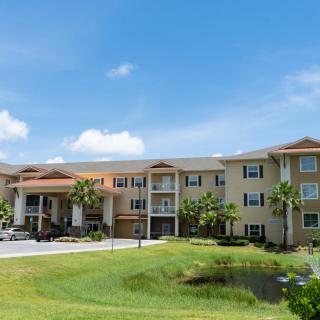 A view of a residential apartment complex with well-maintained landscaping under a clear blue sky.