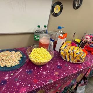 A festive snack table featuring popcorn, drinks, and assorted treats.