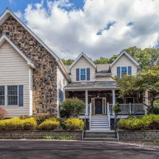 A beautiful residential house with a stone facade and a welcoming porch, surrounded by well-maintained landscaping.