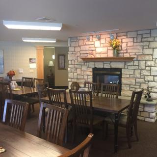 A cozy dining room with wooden furniture and a stone fireplace.