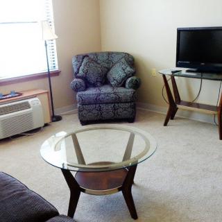 A cozy living room with a chair, TV, and coffee table near a window.