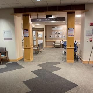 Entrance to a hospital with a waiting area and medical rooms visible.