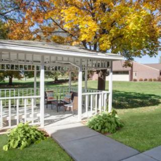 A picturesque gazebo surrounded by autumn trees and a well-maintained lawn.